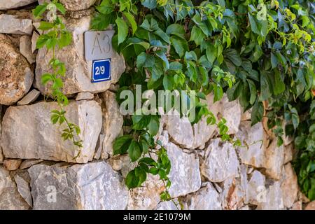 Urlaubsansicht mit Hausnummer und Steinmauer. Stockfoto