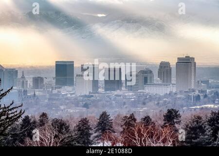 Wolkenkratzer und Gebäude auf einem nebligen Stadtbild mit Blick auf Ein schneebedeckter Berg Stockfoto