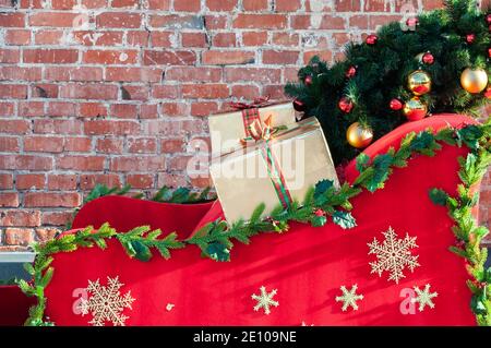 Weihnachtsgeschenke auf einem Schlitten mit goldenen Schneeflocken geschmückt und weihnachtsbaum Brunches Stockfoto