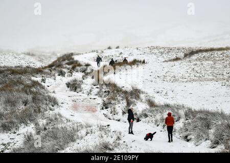 Wanderer steigen den Pfad auf den Gipfel des Pen y Fan, des höchsten Berges von Südwales, bei schneebedeckten Bedingungen auf. Stockfoto