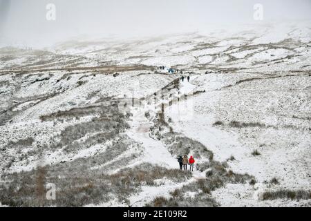 Wanderer steigen den Pfad auf den Gipfel des Pen y Fan, des höchsten Berges von Südwales, bei schneebedeckten Bedingungen auf. Stockfoto