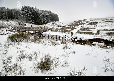 Wanderer überqueren die Brücke, um den Pfad zum Gipfel des Pen y Fan, dem höchsten Berg von Südwales, bei schneebedeckten Bedingungen zu erklimmen. Stockfoto