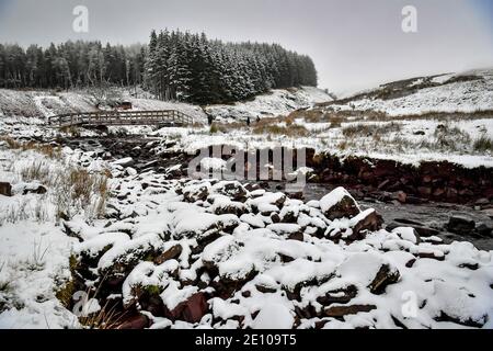 Wanderer überqueren die Brücke, um den Pfad zum Gipfel des Pen y Fan, dem höchsten Berg von Südwales, bei schneebedeckten Bedingungen zu erklimmen. Stockfoto