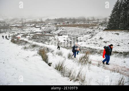 Wanderer steigen den Pfad auf den Gipfel des Pen y Fan, des höchsten Berges von Südwales, bei schneebedeckten Bedingungen auf. Stockfoto