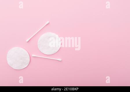 Wattepads mit Baumwollsticks auf rosa Hintergrund, Layout mit Platz für Text Stockfoto
