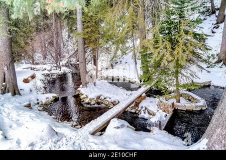 Kleiner felsiger Bach auf hügeligem Gelände mit frischem weißem Schnee In der Wintersaison Stockfoto
