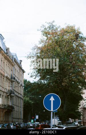 Verkehrsschild vorgeschriebene Richtung geradeaus. Verkehrszeichen zwischen der Straße in der Stadt. Weißer Pfeil auf blauem Hintergrund Stockfoto