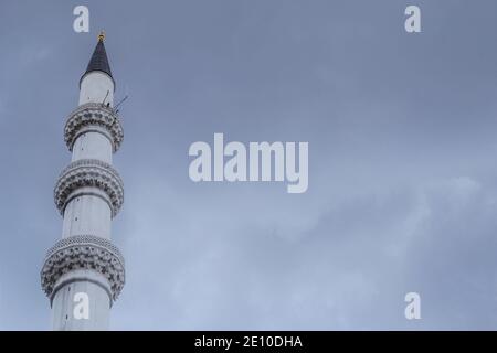 Ein weißes Minarett in grauen Wolken Stockfoto