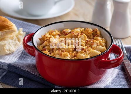 Nahaufnahme einer Schüssel mit Makkaroni und Käse mit Speck Stücke auf Holztisch Stockfoto