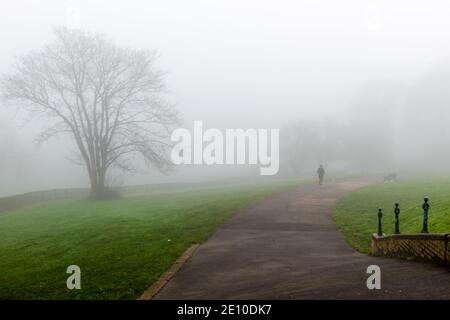 Ein Park, der von starkem Nebel bedeckt ist und von dem Leute ausgehen. Stockfoto