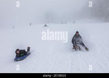 Oberried, Deutschland. Januar 2021. Tom (l) und Justus fahren mit ihren Schlitten in der Nähe des Skilifts am Haldenköpfle die Piste hinunter. Viele nutzen den letzten Tag des langen Neujahrswochenendes für einen Ausflug in den verschneiten Schwarzwald. Quelle: Philipp von Ditfurth/dpa/Alamy Live News Stockfoto