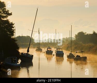 Blick auf einen Sonnenaufgang über dem River Frome und dem Wareham Quay von South Bridge, Wareham, Dorset, England, UK an einem hellen nebligen Morgen. Stockfoto