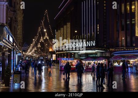 Leute auf Aleksanterinkatu mit Weihnachtsbeleuchtung, Haupteingang des Stockmann Kaufhauses und einige Weihnachtsstände in Helsinki, Finnland Stockfoto