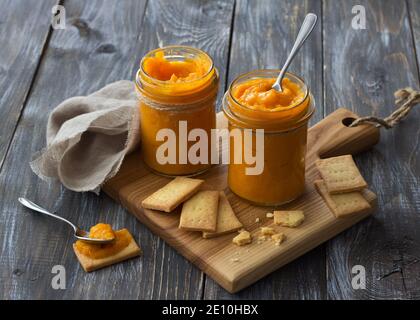 Gesunde rohe Orangenmarmelade mit getrockneten Aprikosen in einem Glas mit Cookies auf einem Holztisch. Diät-Essen. Selektiver Fokus. Rustikaler Stil Stockfoto
