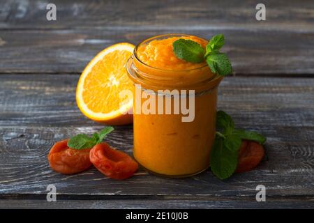 Gesunde rohe Orangenmarmelade mit getrockneten Aprikosen im Glas auf einem Holztisch. Diät-Essen. Selektiver Fokus. Rustikaler Stil Stockfoto
