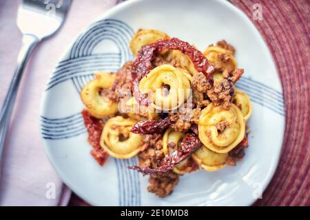 Tortellini mit Bolognese Sauce und getrockneten Tomaten mit Gabel und Serviette, Closeup Stockfoto