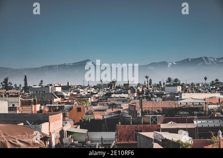 Panoramablick auf Marrakesch Medina und das schneebedeckte Atlasgebirge in Marokko. Blick auf die Dächer von Marrakesch in der Nähe des Stadtzentrums Stockfoto