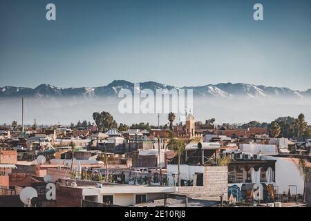 Panoramablick auf Marrakesch Medina und das schneebedeckte Atlasgebirge in Marokko. Blick auf die Dächer von Marrakesch in der Nähe des Stadtzentrums Stockfoto