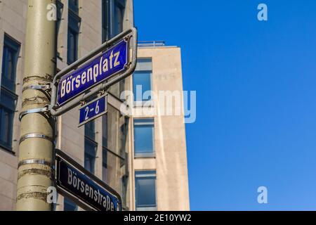 Blaues Verkehrszeichen Börsenplatz und Börsenstraße auf einer grauen Laternenpfosten mit Befestigungen. Haus mit Fensterfassade im Hintergrund mit blau Stockfoto