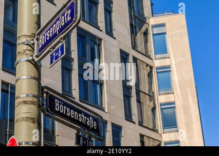 Zwei blaue Straßenschilder Börsenplatz und Börsenstraße auf einem grauen Laternenpfosten mit Befestigungen. Haus mit Fensterfassade im Hintergrund Stockfoto