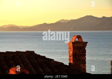 Detail des Daches eines alten Hauses in der alten Zitadellenstadt von Monemvassia, Griechenland, bei Morgendämmerung mit dem Meer und den Bergen im Hintergrund Stockfoto