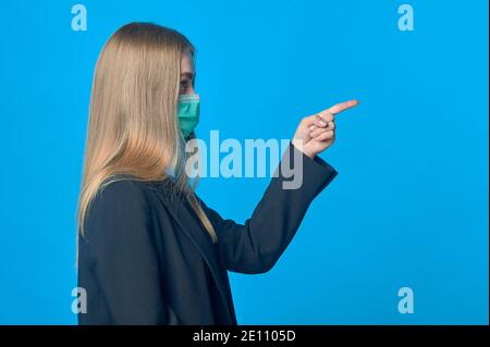 Ein Mädchen in einer medizinischen Maske weist auf etwas hin Stockfoto