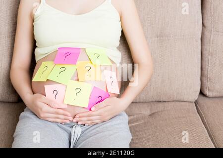 Schwangere Frau Bauch mit Fragezeichen. Schwangerschaft und Denkproblem. Stockfoto