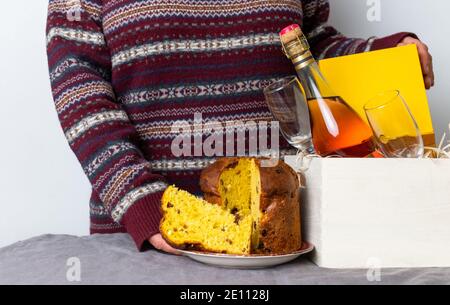 Weibliche Hand hält ostern Panetone italienische Stück in der Nähe Lieferbox mit Champagner-Flasche. Stockfoto