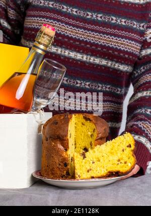 Weibliche Hand hält ostern Panetone italienische Stück in der Nähe Lieferbox mit Champagner-Flasche. Stockfoto