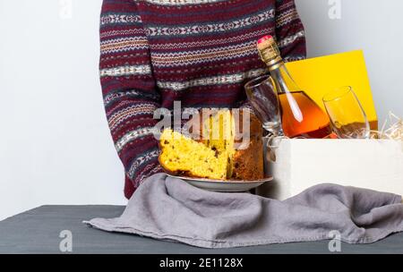 Weibliche Hand hält ostern Panetone italienische Stück in der Nähe Lieferbox mit Champagner-Flasche. Stockfoto