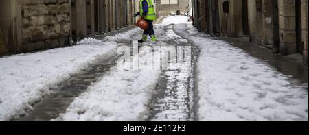 Mann gießt Salzschnee, Leute arbeiten weihnachten, Winter Stockfoto