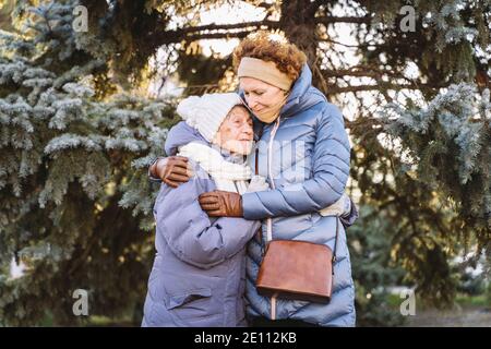 Kaukasische Frauen ältere Mutter und reife Tochter im Wintergarten auf Hintergrund Tannenbaum umarmen sich von Angesicht zu Angesicht, Lächeln, Zeit mit alten Passe verbringen Stockfoto
