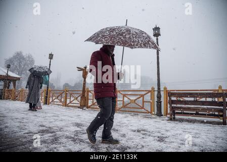 Srinagar, Indien. Januar 2021. Ein Mann, der einen Regenschirm hält, geht entlang einer Brücke inmitten von starkem Schneefall in Srinagar.die Kaschmir-Region erhielt frischen Schneefall am Sonntag, der die Temperaturen drastisch herunterbringt und den Luft- und Fahrzeugverkehr beeinflusst. Der Schneefall wird sich vom 3. Bis 6. Januar mit gelegentlichen Pausen fortsetzen, sagten Met-Beamte. Kredit: SOPA Images Limited/Alamy Live Nachrichten Stockfoto