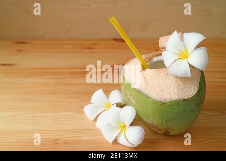 Frischer junger Kokosnusssaft mit Frangipani-Blumen auf einem hölzernen Tabelle Stockfoto