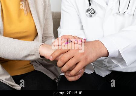 Nahaufnahme des Doctors Hände halten Patienten Hand im Büro, sitzen auf dem Sofa Stockfoto