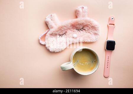 Schlafmaske und Kaffeetasse auf rosa Hintergrund. Das Konzept des Starts eines neuen Tages, guten Morgen oder Ende des Tages, späten Abend. Stockfoto