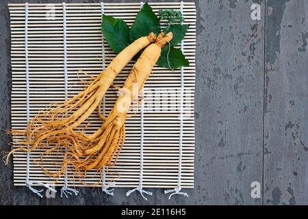 Frische Ginseng Wurzel auf Bambus Korb mit grünen Blättern und Beeren Stockfoto