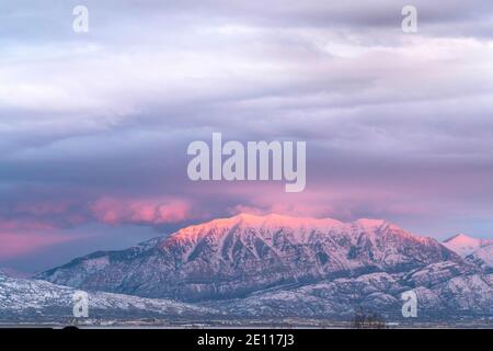 Neblige Landschaft von majestätischen schneebedeckten Berg im Winter mit Sonnenlicht Höhepunkt bei Sonnenuntergang Stockfoto