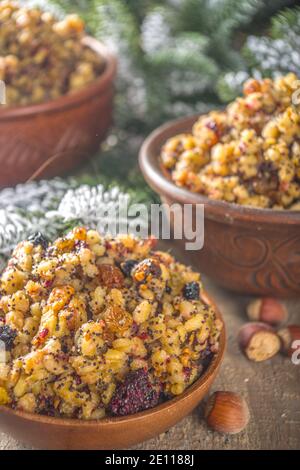 Osteuropäische, russische, ukrainische, slawische traditionelle Weihnachtsessen, süße kutya, mit getrockneten Früchten, Mohnsamen und Nüssen. Holzhintergrund mit Chri Stockfoto