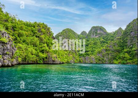 Blaues Kristallwasser im Paradies Bucht mit Booten auf dem hölzernen Pier am Kayangan See in Coron Insel, tropisches Reiseziel - Palawan, Philippinen. Stockfoto