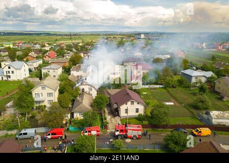 Luftaufnahme eines brennenden Hauses mit orangen Flammen und weißem dicken Rauch. Stockfoto