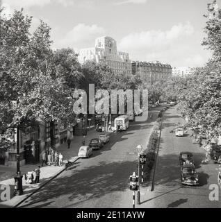 1950er Jahre, Blick von oben aus dieser Zeit, entlang der von Bäumen gesäumten Victoria Embankment, neben der Themse, mit einem alten Stil "Polizei-Box" auf der unteren linken Seite und die berühmte Uhr auf der Südseite des Shell Mex House - auch bekannt als 80 Strand - in der Ferne gesehen, London, England, VEREINIGTES KÖNIGREICH. Stockfoto