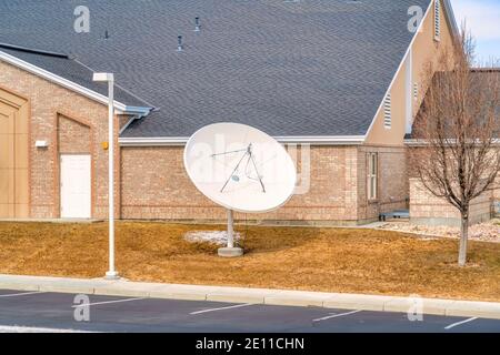 Parabolantenne auf Rasen vor dem Gebäude Mit Ziegelwand Stockfoto