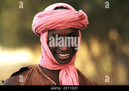 Ein junger Mann mit einem rosa Turban lächelt in Mali, Westafrika. Stockfoto