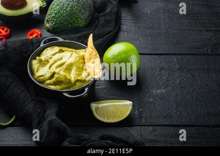 Nachos Mais-Tortilla-Chip mit Avocado-Dip oder Guacamole in Schale, auf schwarzem Holzhintergrund mit Platz für Text Stockfoto