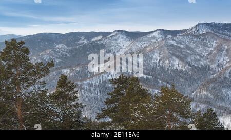 Sanfte Hänge der Waldhügel sind mit ersten Schnee bedeckt. Blick auf Bergtäler und Bergrücken am Horizont. Stockfoto