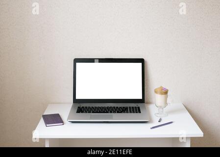 Arbeitsplatz eines Bloggers oder Freiberuflers, Büroangestellter. Dalgona Kaffee in einer klaren Tasse, Notizblock, Stift und Computer auf dem Tisch. Mockup- und Kopierbereich Stockfoto