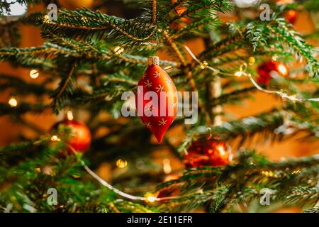 Weihnachtsbaum mit rot glänzender Kugel. Festliche Weihnachten Ornament hängen auf Baum verschwommen Hintergrund.traditionelle Feiertag dekorative Szene. Heiligabend Stockfoto