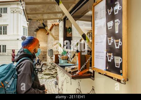 Kaukasischer Mann in den Straßen der Stadt mit einer Gesichtsmaske Gegen kovid19 Coronavirus Kauf Kaffee zum Mitnehmen.Erwachsener mit chirurgischer Maske gegen Virus SARS-CoV Stockfoto