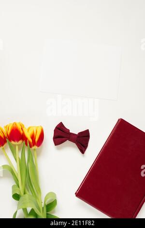 Hintergrund zum Valentinstag. Muttertag oder Frühling. Burgunder Notizbuch, Schleife, Blumen auf weißem Hintergrund, Draufsicht. Freier Speicherplatz für das Textfeld, Stockfoto